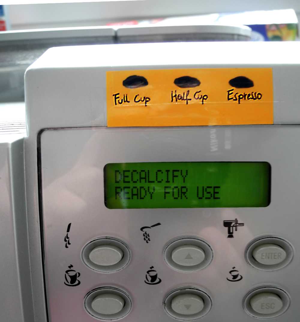 A coffee machine with added instructions on a orange note, telling that the buttons are for “Full Cup”, “Half Cup”, “Espresso”